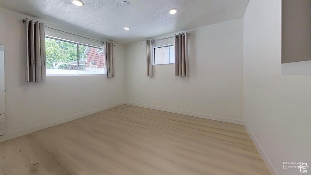 Spare room featuring light wood-style flooring, a textured ceiling, recessed lighting, and baseboards