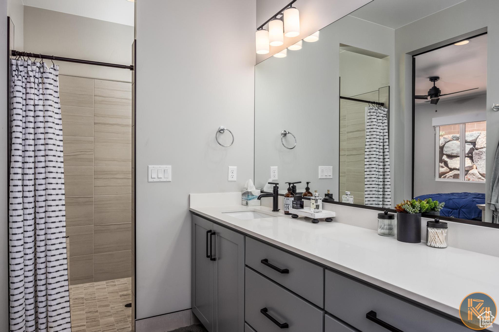 Bathroom featuring ceiling fan, a stall shower, and vanity