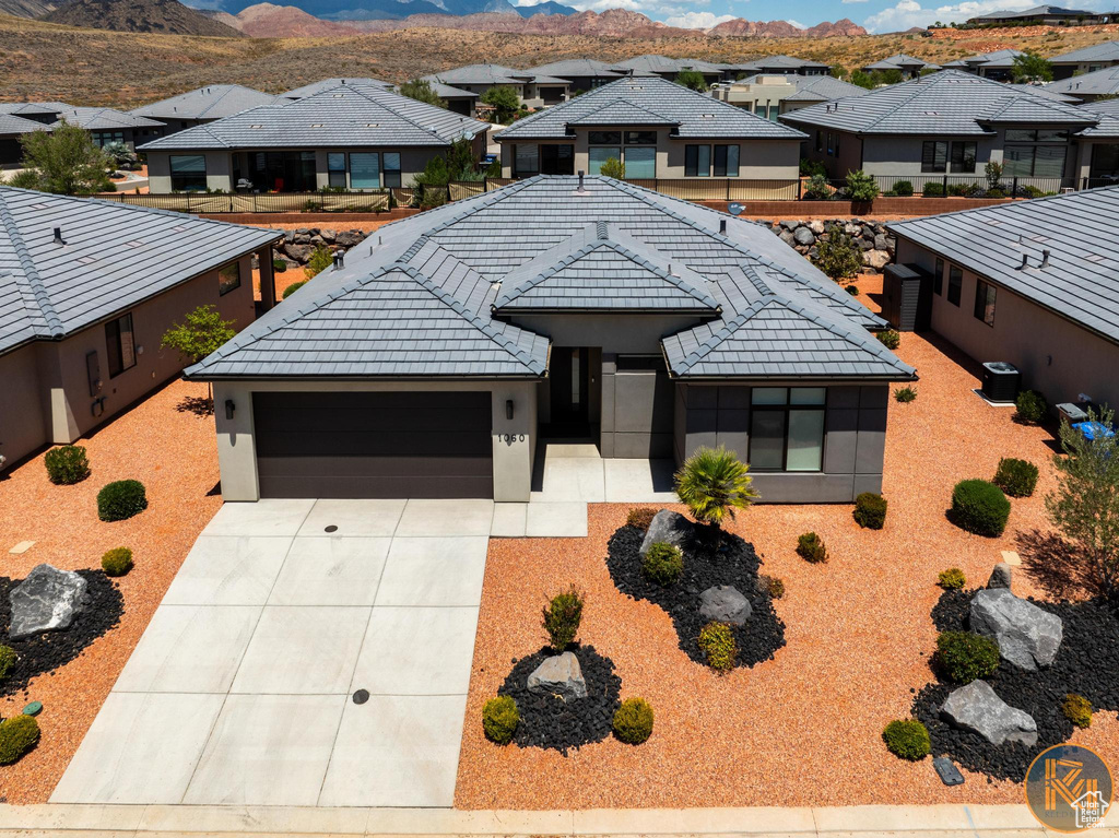 View of front facade with a residential view, stucco siding, an attached garage, driveway, and a mountain view