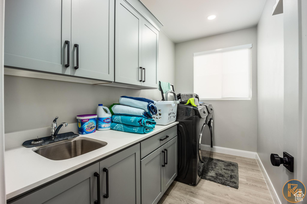 Laundry room featuring washing machine and clothes dryer, cabinet space, light wood-style flooring, baseboards, and recessed lighting