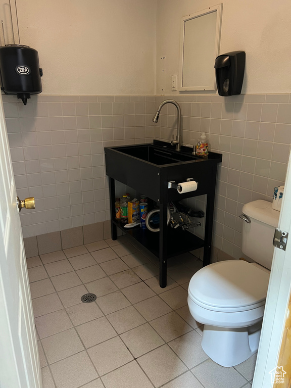 Bathroom featuring tile walls, toilet, tile patterned flooring, wainscoting, and vanity