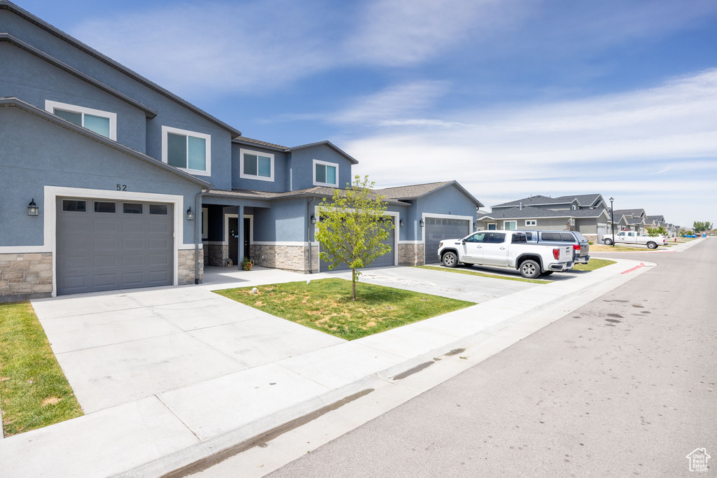 View of front facade with stone siding, stucco siding, a residential view, and concrete driveway