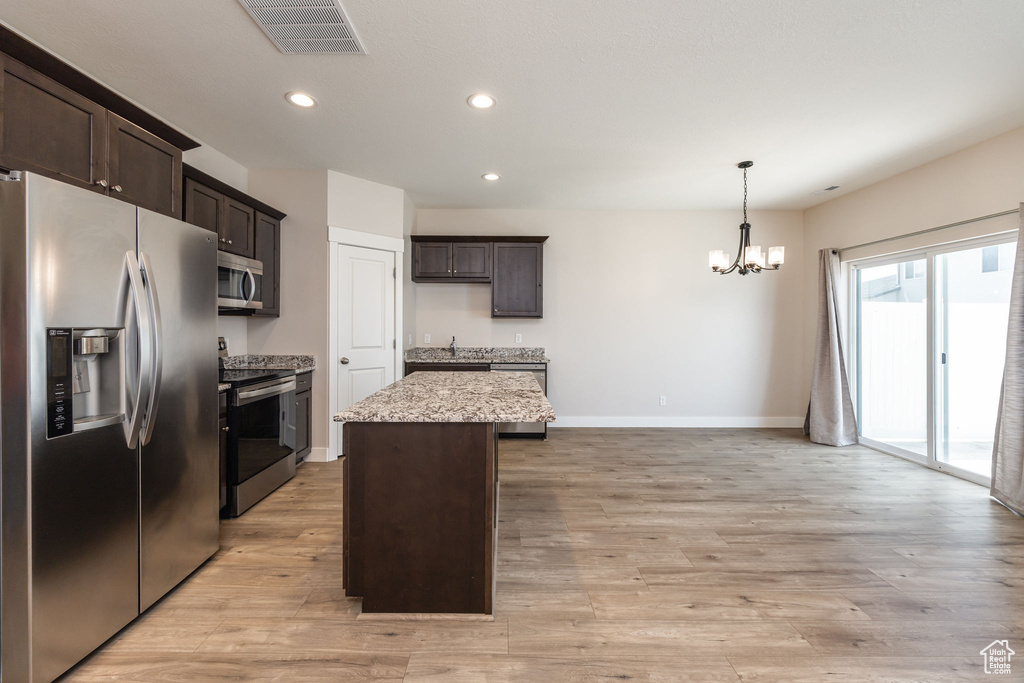 Kitchen with stainless steel appliances, a chandelier, dark brown cabinets, a center island, and baseboards