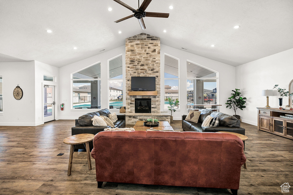 Living room featuring a ceiling fan, dark wood-style flooring, baseboards, vaulted ceiling, and a large fireplace