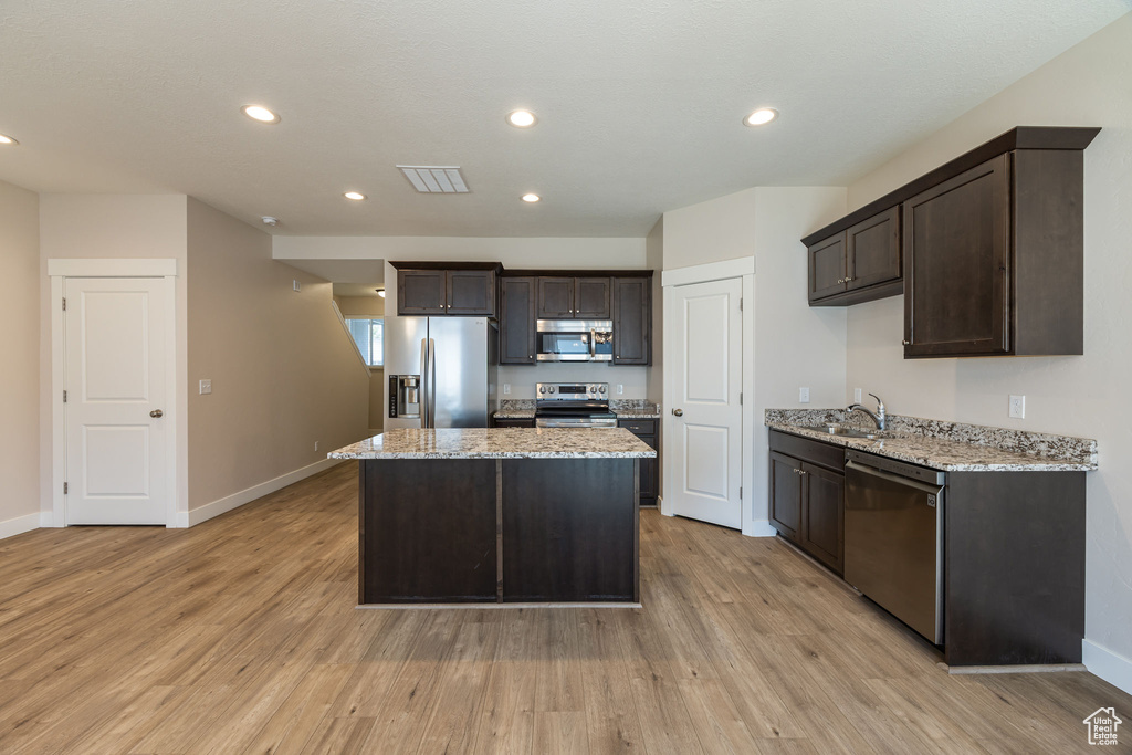 Kitchen with stainless steel appliances, dark brown cabinets, a sink, a center island, and recessed lighting