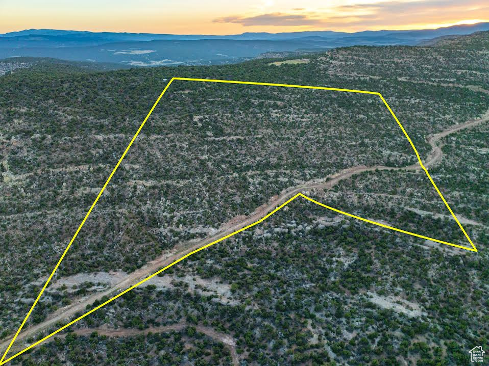 Aerial overview of property\'s location featuring a mountainous background and property parcel outlined