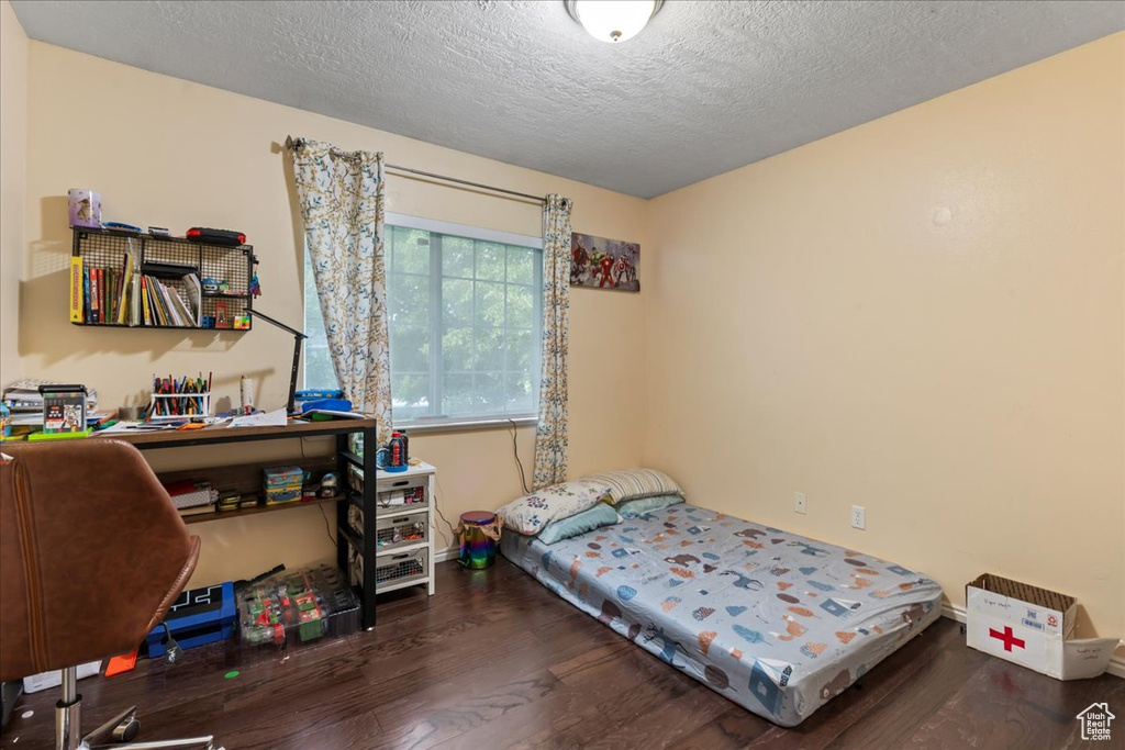 Bedroom with wood finished floors and a textured ceiling