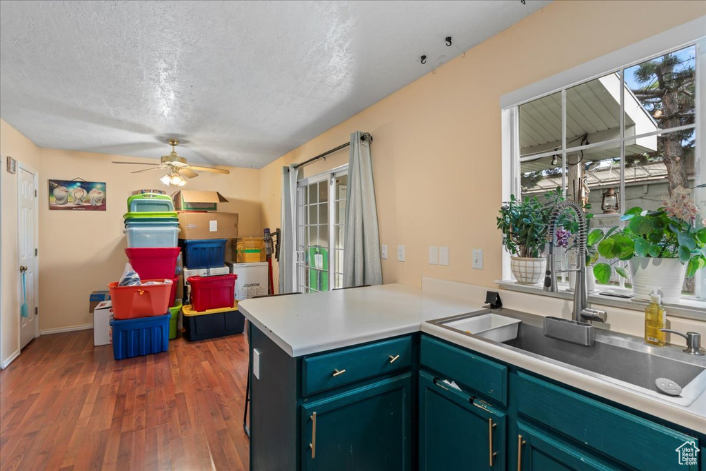 Kitchen featuring a peninsula, a sink, wood finished floors, a textured ceiling, and a ceiling fan
