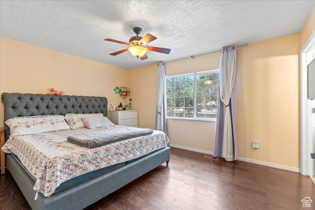 Bedroom with baseboards, a textured ceiling, wood finished floors, and ceiling fan
