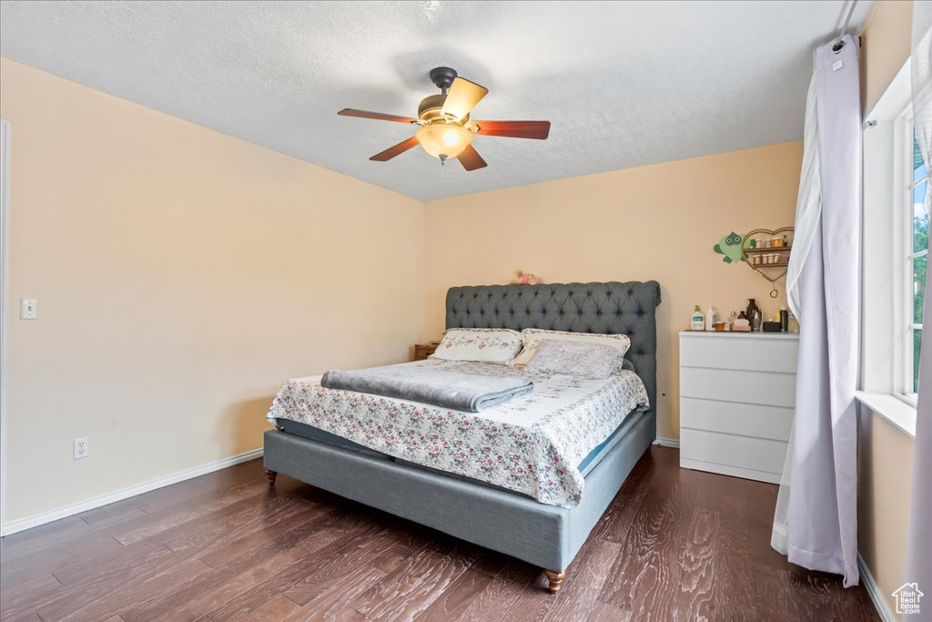 Bedroom with wood finished floors, baseboards, a ceiling fan, and a textured ceiling