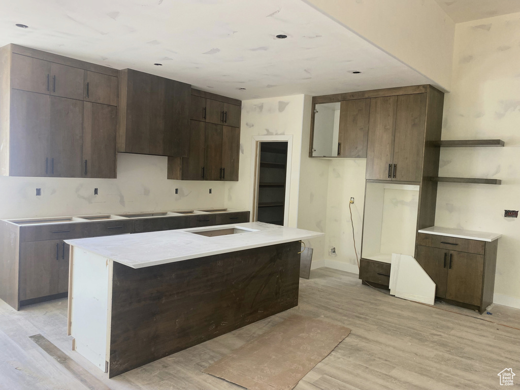 Kitchen with light wood-style flooring, baseboards, dark brown cabinetry, and a kitchen island