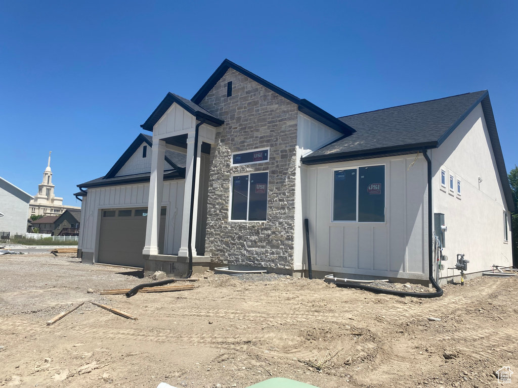 View of front of house featuring board and batten siding, a garage, and stone siding
