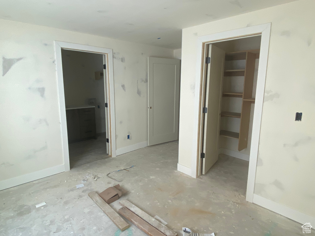 Unfurnished bedroom with a spacious closet, baseboards, a closet, and connected bathroom