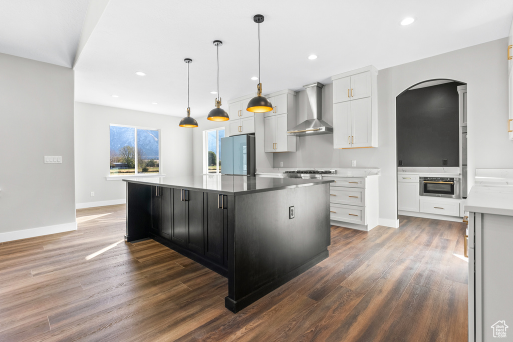 Kitchen featuring wall chimney exhaust hood, smart refrigerator, wood finished floors, arched walkways, and baseboards