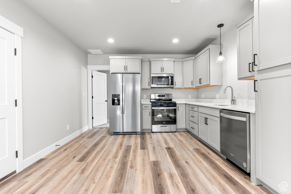 Kitchen featuring stainless steel appliances, a sink, light wood-style floors, recessed lighting, and pendant lighting