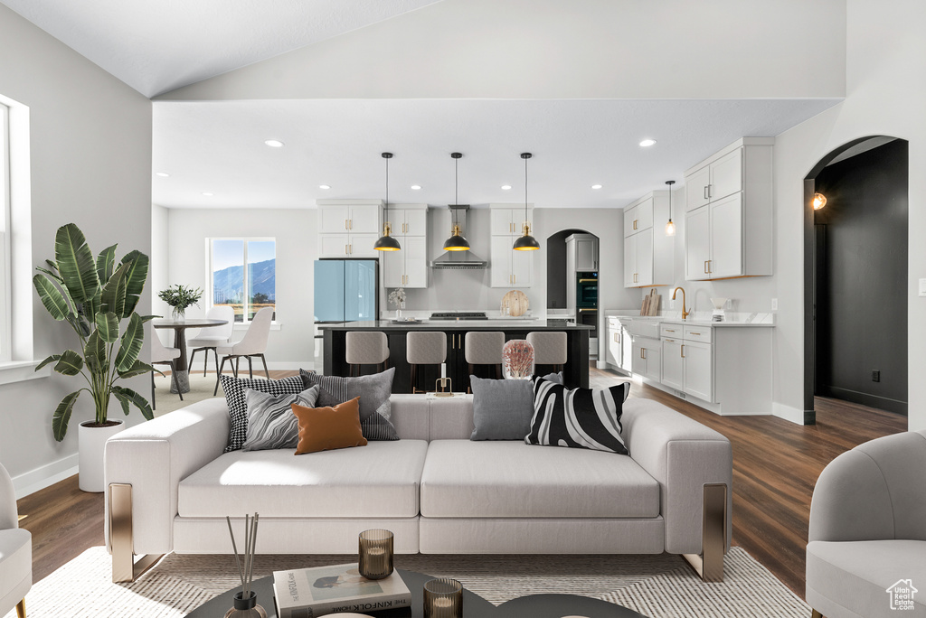 Living area featuring arched walkways, dark wood-style flooring, recessed lighting, baseboards, and lofted ceiling