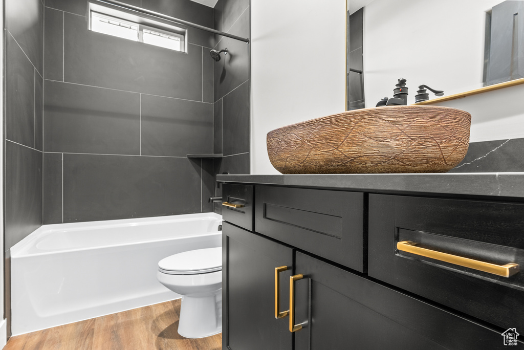 Bathroom with toilet, wood finished floors, and washtub / shower combination