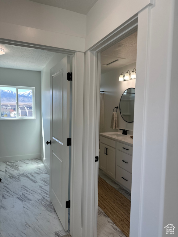 Bathroom with marble look tiles, vanity, baseboards, and a textured ceiling