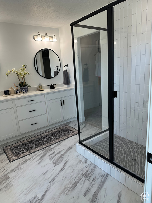 Bathroom featuring marble finish floors, vanity, a stall shower, and a textured ceiling