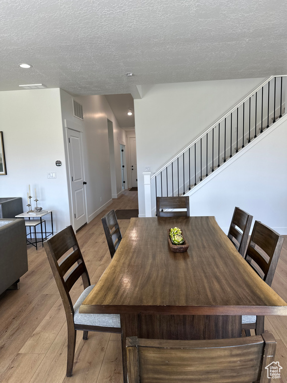 Dining space featuring stairs, light wood-style flooring, a textured ceiling, and recessed lighting