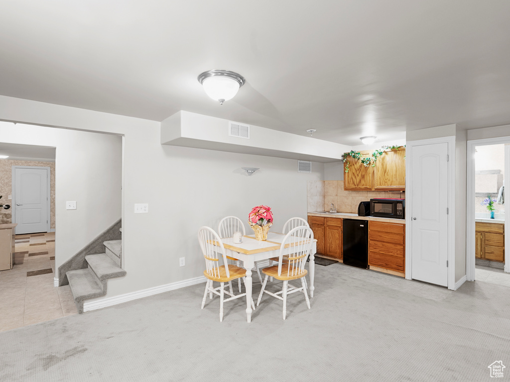Dining space with baseboards, stairs, light colored carpet, and light tile patterned floors