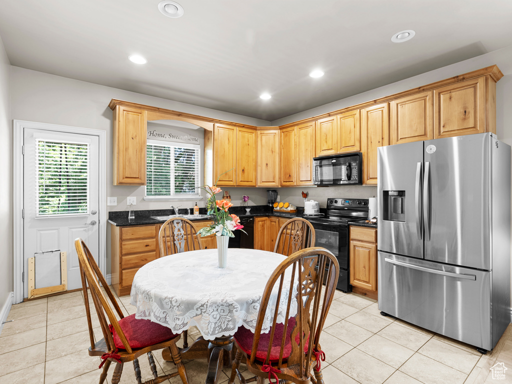 Kitchen featuring black appliances, dark countertops, light tile patterned floors, recessed lighting, and light brown cabinetry