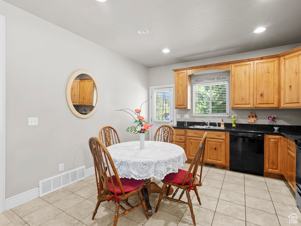 Kitchen featuring dishwasher, dark countertops, light tile patterned floors, recessed lighting, and a sink