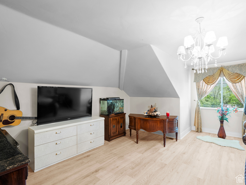 Living area with wood finished floors, a chandelier, vaulted ceiling, and baseboards