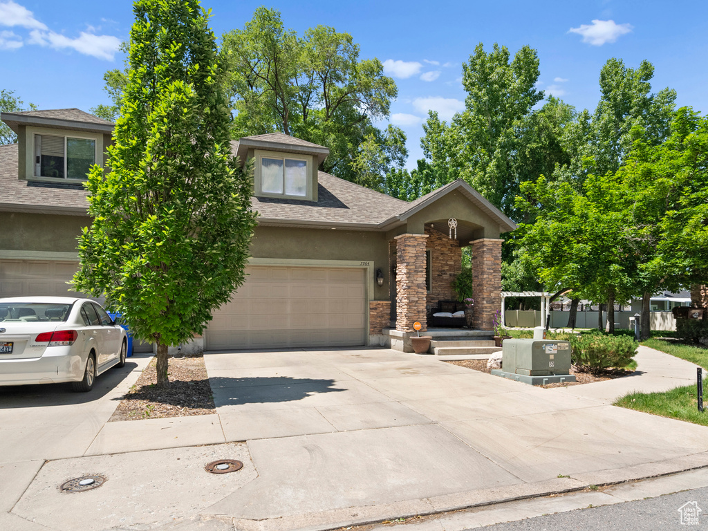 View of front of house featuring stucco siding, concrete driveway, a shingled roof, a garage, and stone siding