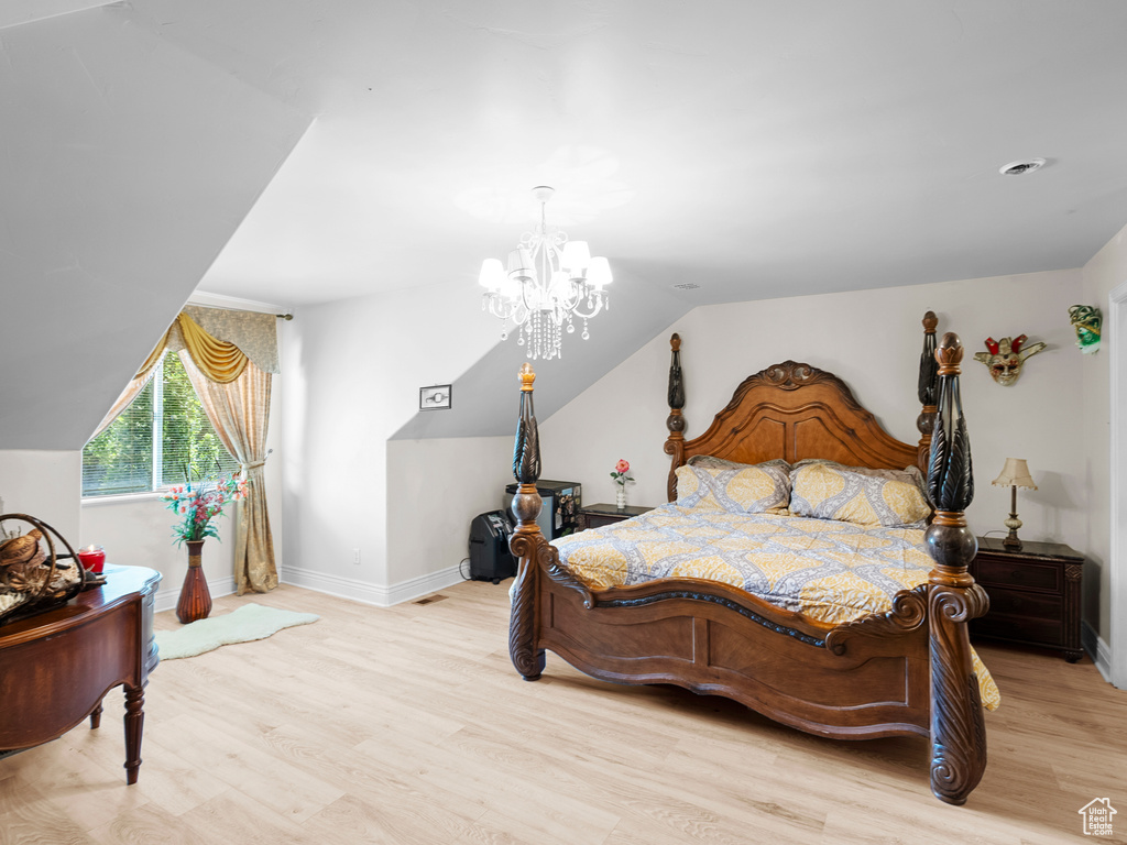 Bedroom featuring light wood finished floors, a chandelier, vaulted ceiling, and baseboards