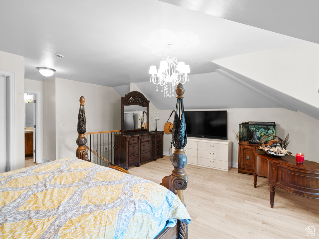 Bedroom featuring a chandelier, wood finished floors, and vaulted ceiling