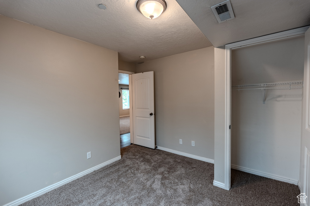 Unfurnished bedroom with carpet, a closet, baseboards, and a textured ceiling