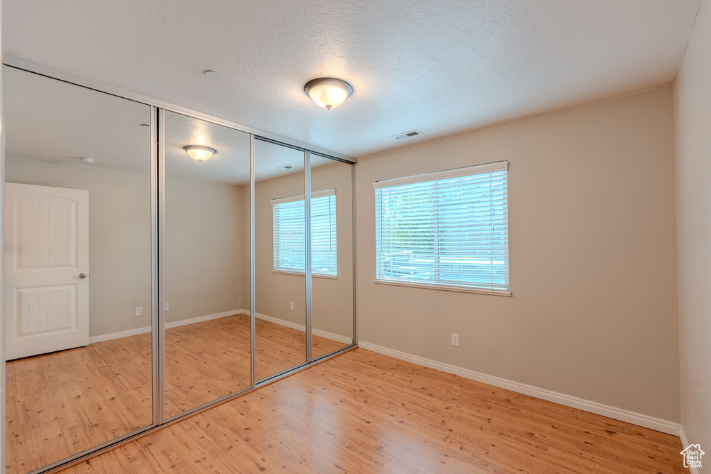 Unfurnished bedroom featuring wood finished floors, baseboards, and a closet