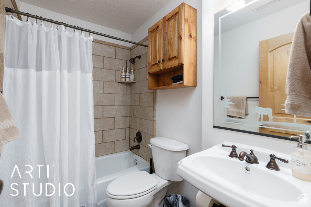 Bathroom featuring a sink, toilet, and shower / bath combo with shower curtain