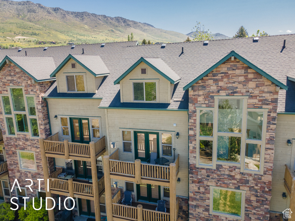 View of front of home with a mountain view, a balcony, and stone siding
