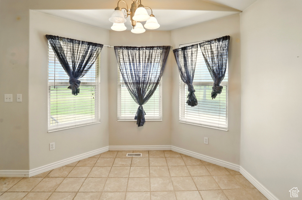 Spare room featuring a chandelier, baseboards, and light tile patterned floors