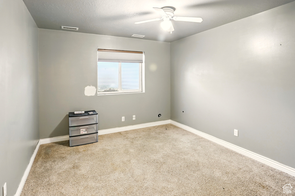 Carpeted spare room with ceiling fan and baseboards