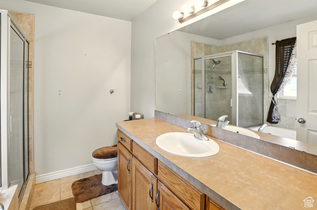 Bathroom featuring toilet, vanity, a stall shower, and tile patterned floors