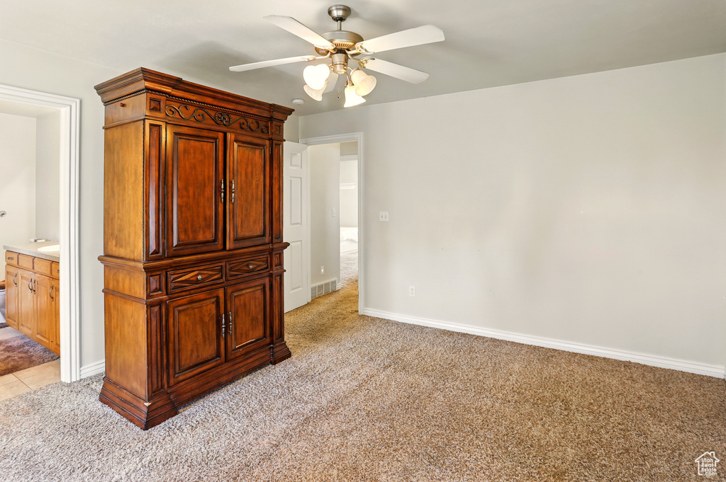 Unfurnished bedroom with light carpet, baseboards, a ceiling fan, and connected bathroom