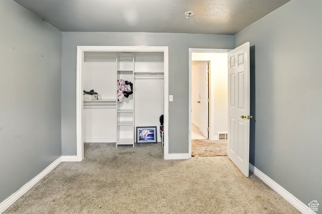 Unfurnished bedroom featuring carpet floors, a closet, and baseboards