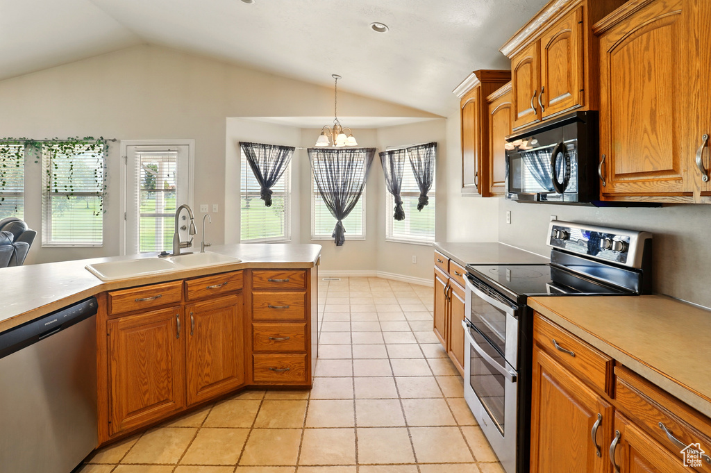 Kitchen with appliances with stainless steel finishes, a sink, lofted ceiling, decorative light fixtures, and light tile patterned floors