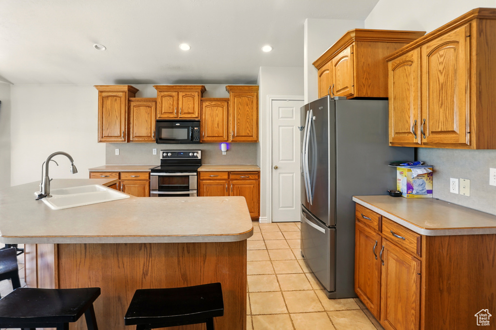 Kitchen featuring stainless steel appliances, a sink, light tile patterned floors, light countertops, and recessed lighting