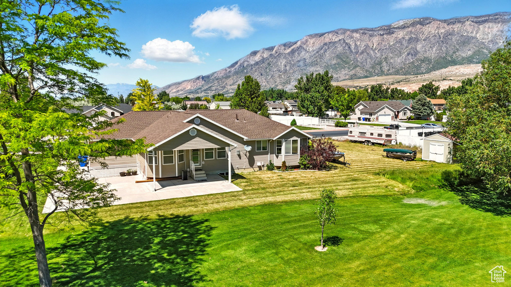 Back of house featuring a patio area, entry steps, a lawn, and a mountain view