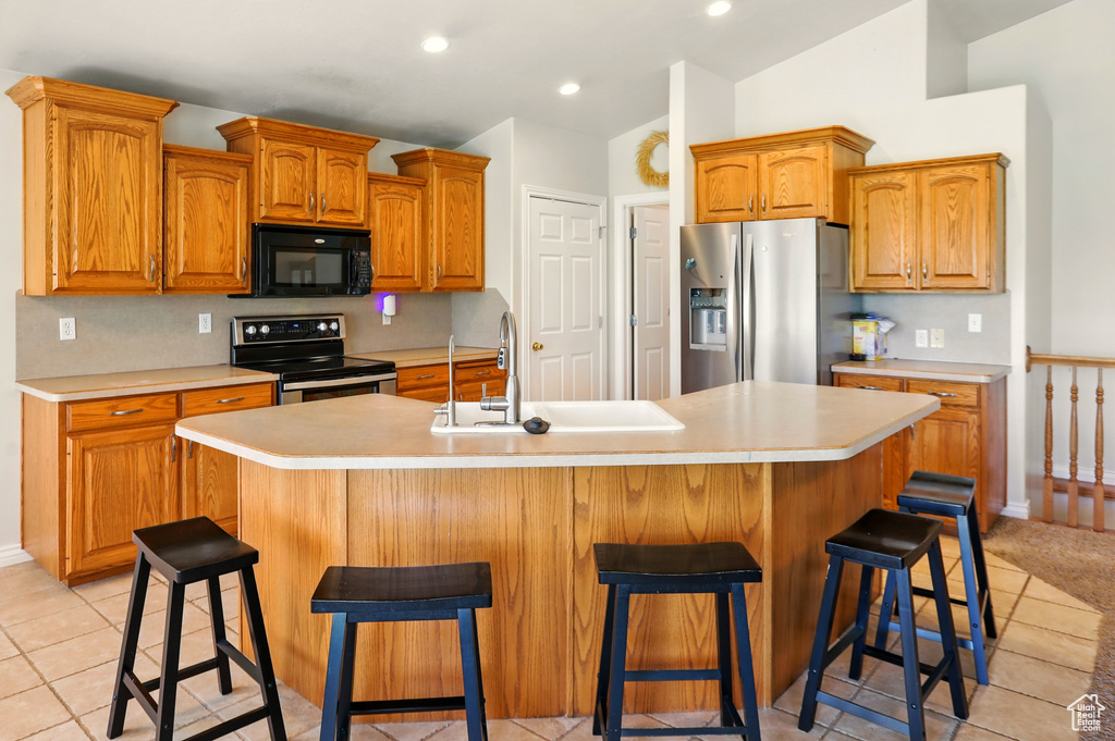 Kitchen featuring appliances with stainless steel finishes, a sink, light countertops, light tile patterned floors, and recessed lighting