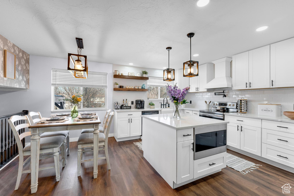 Kitchen featuring custom exhaust hood, electric stove, built in microwave, dark wood-type flooring, and recessed lighting