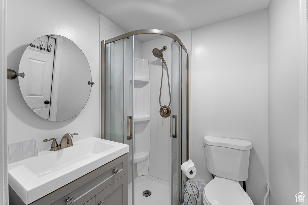 Bathroom featuring toilet, a shower stall, and vanity