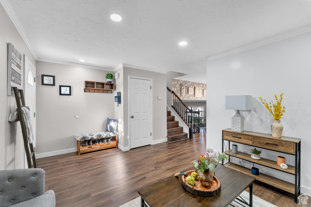 Living room featuring wood finished floors, stairs, baseboards, ornamental molding, and recessed lighting