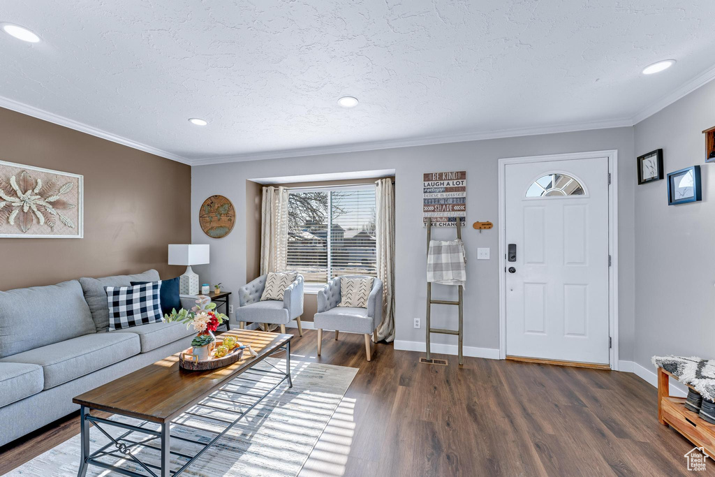 Living room with dark wood finished floors, crown molding, baseboards, and recessed lighting