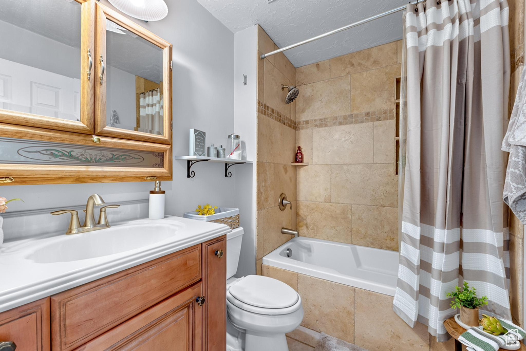 Bathroom with toilet, tiled shower / bath, and vanity