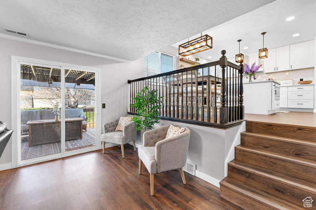 Stairs with a chandelier, wood finished floors, ornamental molding, recessed lighting, and baseboards